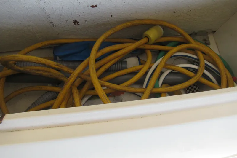 Slide: The Image of Yellow hose and cables stored in a compartment of a 2001 Searay 280 Sundancer boat. - 46
