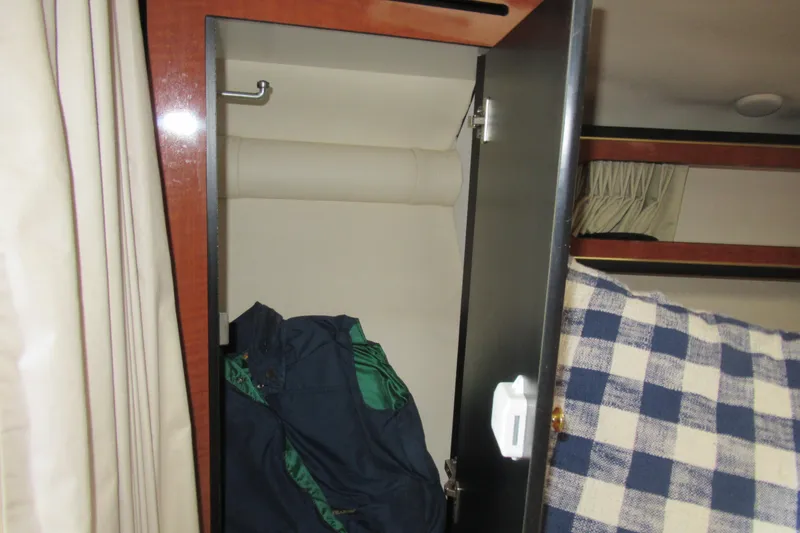 Slide: The Image of 2001 Searay 280 Sundancer cabin closet with hanging clothes and checkered bedding. - 53