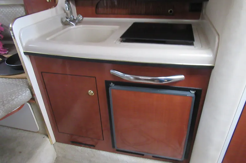 Slide: The Image of 2001 Searay 280 Sundancer kitchenette with sink, stove, and storage. - 58