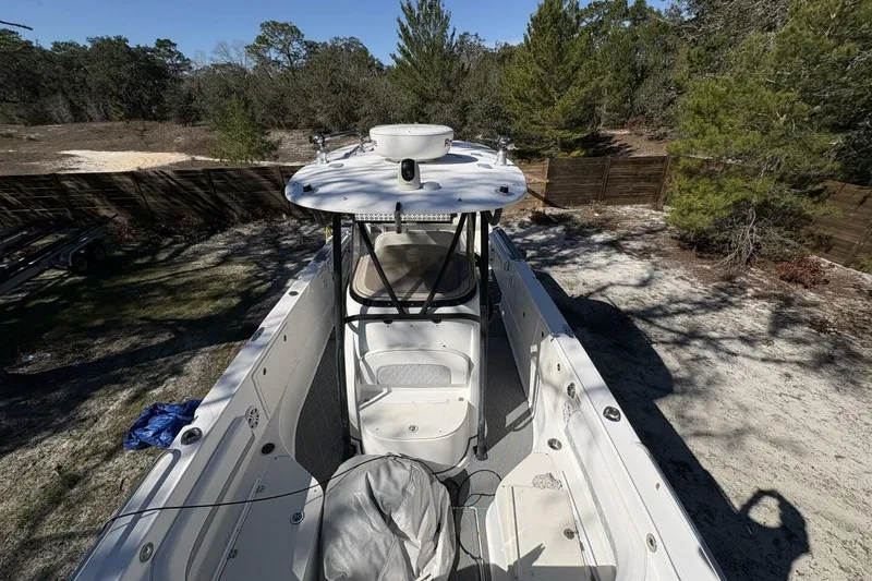 Slide: The Image of 2008 Wellcraft 35 Scarab Sport boat, white exterior, parked outdoors, surrounded by trees. - 10
