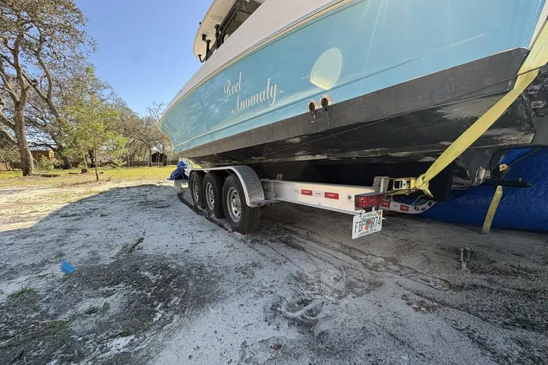 Slide: The Image of 2008 Wellcraft 35 Scarab Sport boat on trailer, parked on sandy ground. - 105