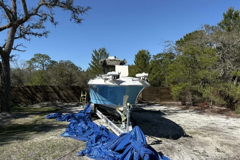 Slide: The Image of 2008 Wellcraft 35 Scarab Sport boat on trailer, surrounded by trees and blue tarp. - 108