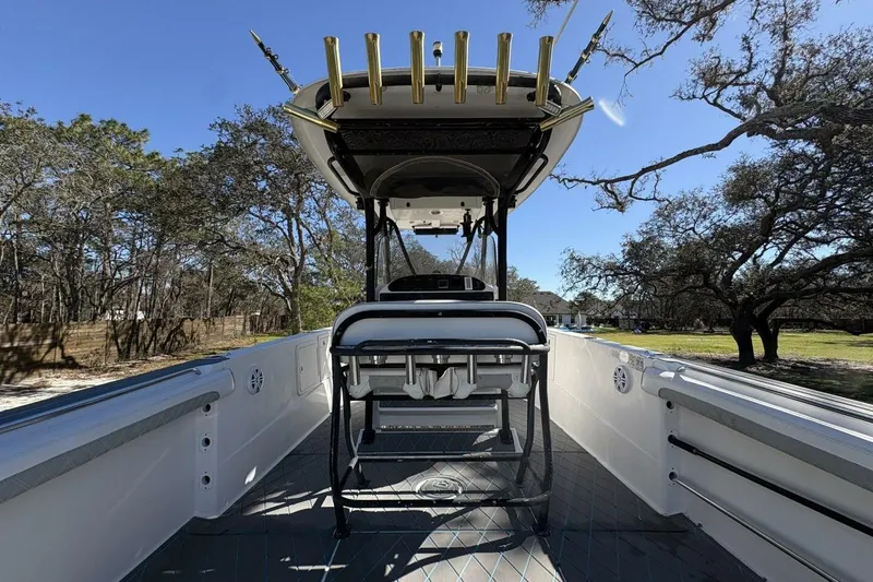 Slide: The Image of 2008 Wellcraft 35 Scarab Sport boat interior with rod holders, surrounded by trees. - 54