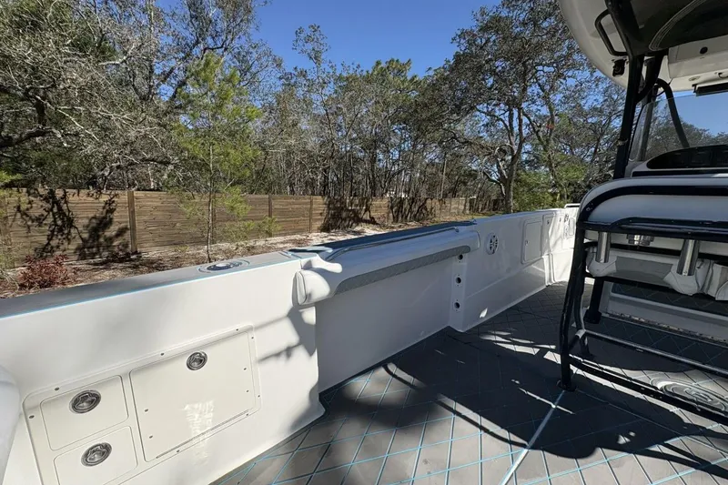 Slide: The Image of 2008 Wellcraft 35 Scarab Sport boat interior with seating and storage, surrounded by trees. - 56