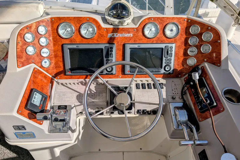 Slide: The Image of 1994 Cruisers Yachts 3850 Aft Cabin helm with gauges, steering wheel, and navigation equipment. - 11