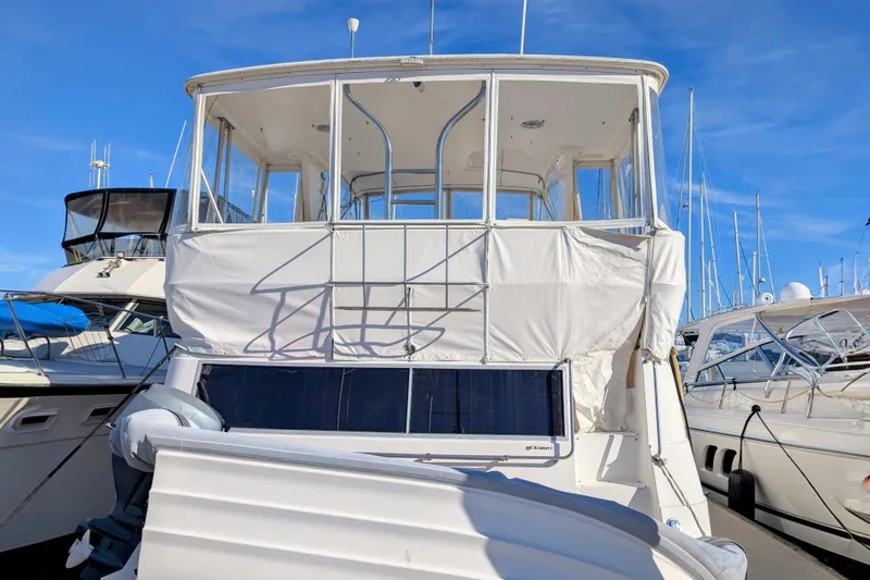 Slide: The Image of 1994 Cruisers Yachts 3850 Aft Cabin docked, featuring spacious upper deck and clear blue sky. - 21