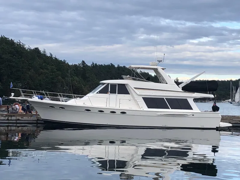The Image of 2003 Meridian 490 Pilothouse yacht docked on calm water, surrounded by trees. - 0