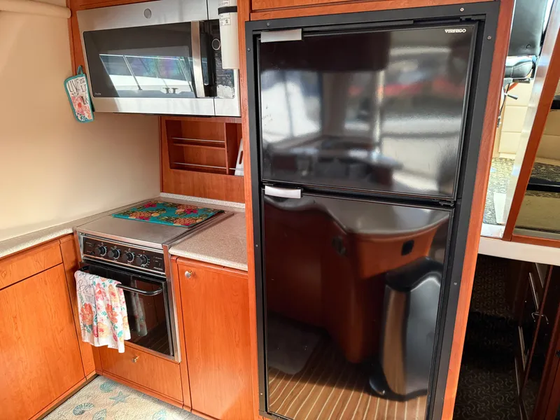 Slide: The Image of 2003 Meridian 490 Pilothouse kitchen with microwave, stove, and refrigerator. - 11