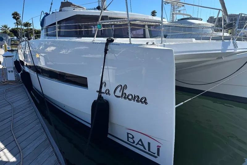 Slide: The Image of 2017 Bali 4.0 catamaran named "La Chona" docked at a marina. - 2