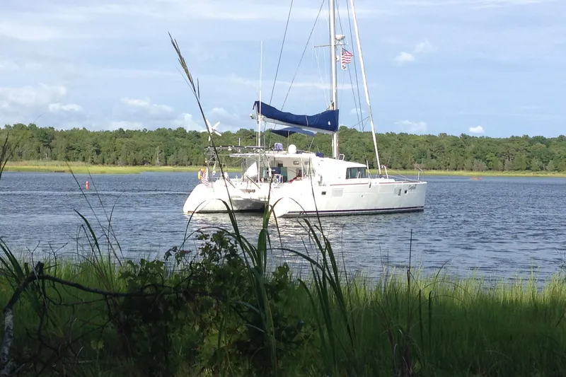 The Image of 2008 Lagoon 440 catamaran anchored on a serene lake with lush greenery. - 0