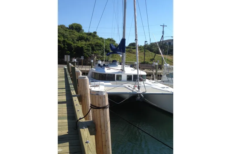 Slide: The Image of 2008 Lagoon 440 catamaran docked at a marina, surrounded by lush greenery. - 26