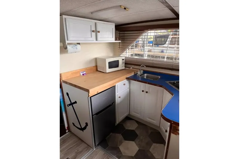 Slide: The Image of 1979 Chris-Craft 350 Catalina kitchen with microwave, sink, and anchor-themed decor. - 3