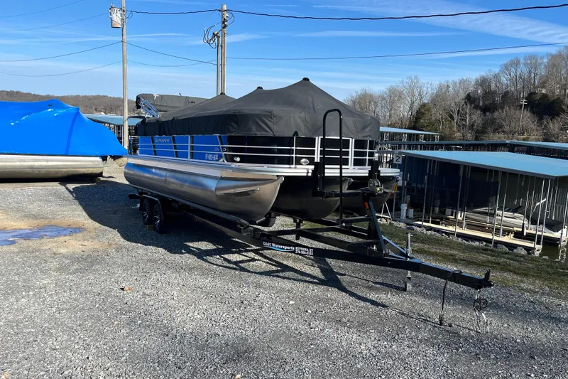 The Image of 2023 Berkshire 24RFX LE pontoon boat on trailer, covered, in marina setting. - 0