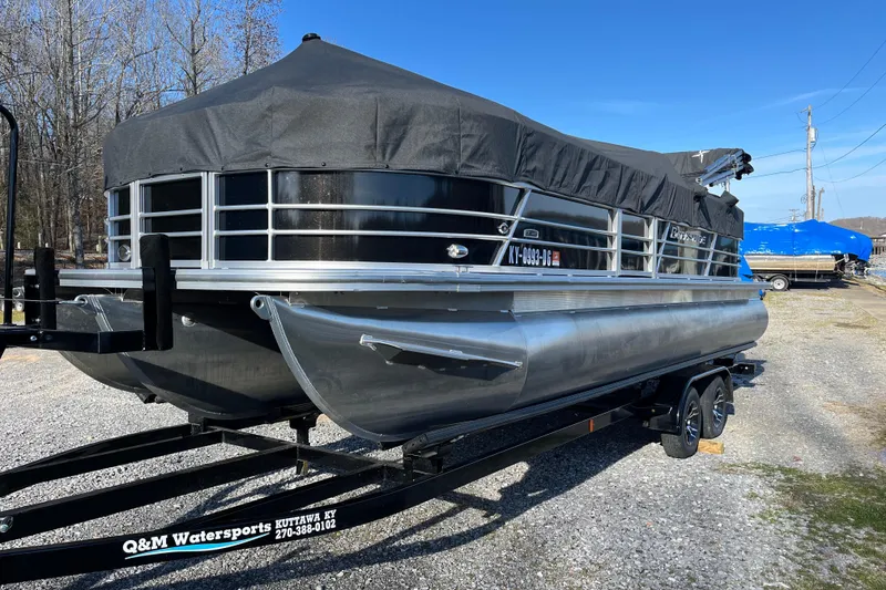 Slide: The Image of 2023 Berkshire 24RFX LE pontoon boat on trailer, covered, parked outdoors. - 2