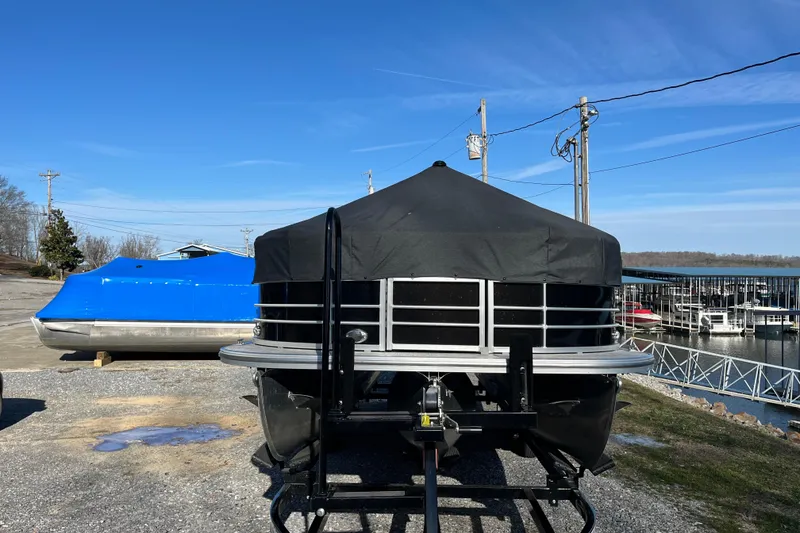Slide: The Image of 2023 Berkshire 24RFX LE pontoon boat covered, parked near a marina under clear blue skies. - 4
