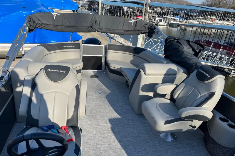 Slide: The Image of 2023 Berkshire 24RFX LE pontoon boat interior with gray seating and helm, docked at marina. - 5