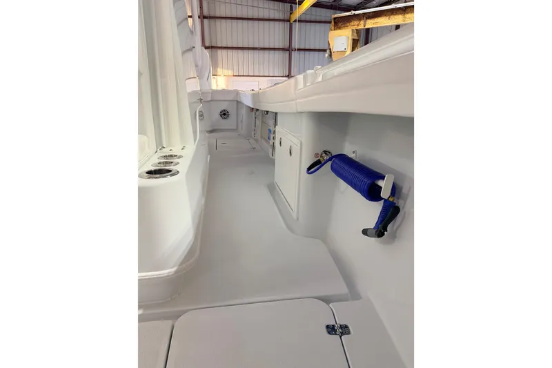 Slide: The Image of 2026 Yellowfin 32 Offshore boat interior with storage and hose, in a warehouse setting. - 11