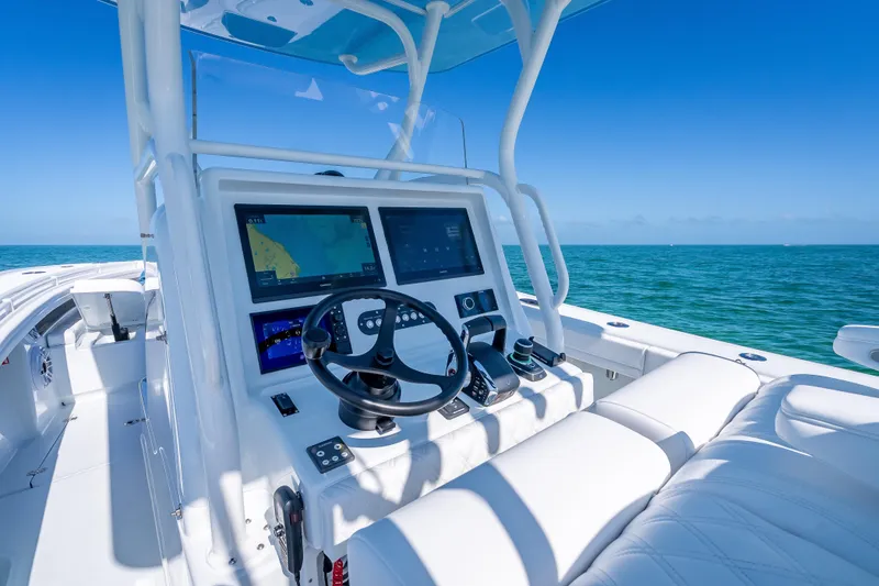 Slide: The Image of 2026 Yellowfin 32 Offshore boat dashboard with navigation screens, steering wheel, and ocean view. - 15