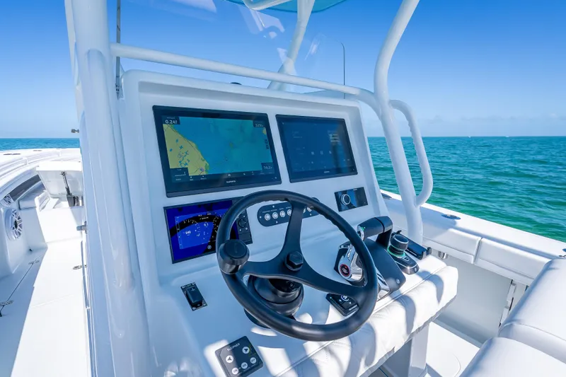 Slide: The Image of 2026 Yellowfin 32 Offshore boat dashboard with navigation screens, steering wheel, and ocean view. - 18