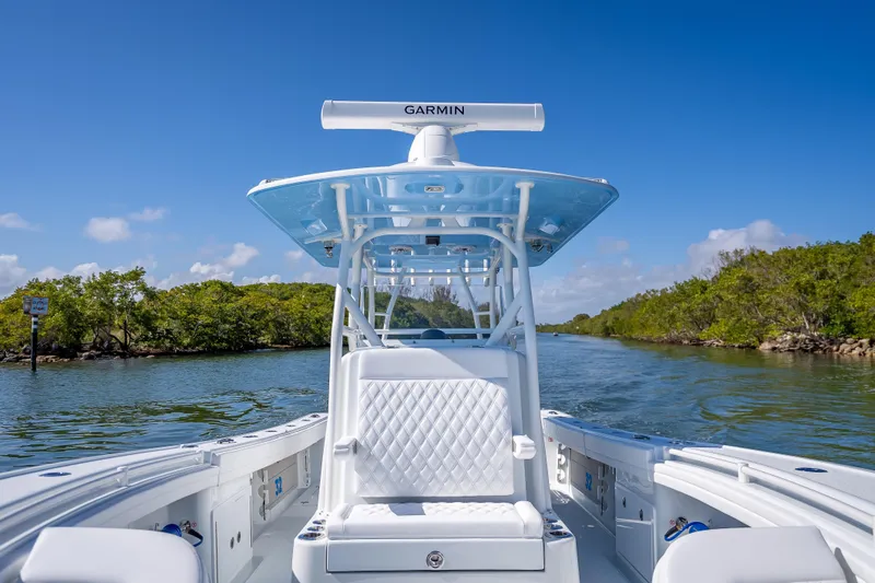 Slide: The Image of 2026 Yellowfin 32 Offshore boat navigating a scenic waterway under clear blue skies. - 32