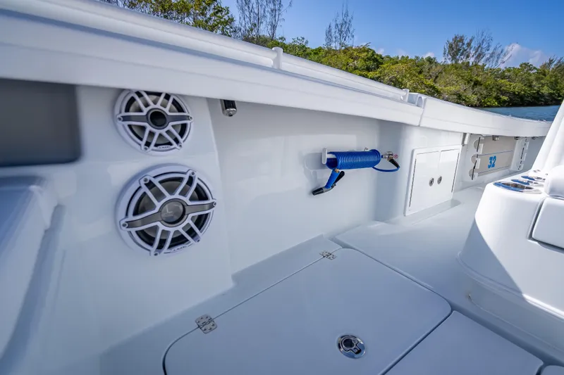Slide: The Image of 2026 Yellowfin 32 Offshore boat interior with speakers and hose, surrounded by lush greenery. - 43