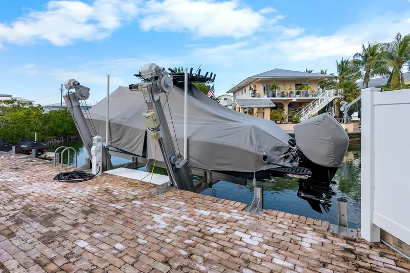Slide: The Image of Covered 2024 Yellowfin 26 Hybrid boat on lift by waterfront home. - 32