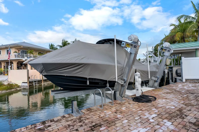 Slide: The Image of 2024 Yellowfin 26 Hybrid boat covered and docked by a waterfront home. - 34