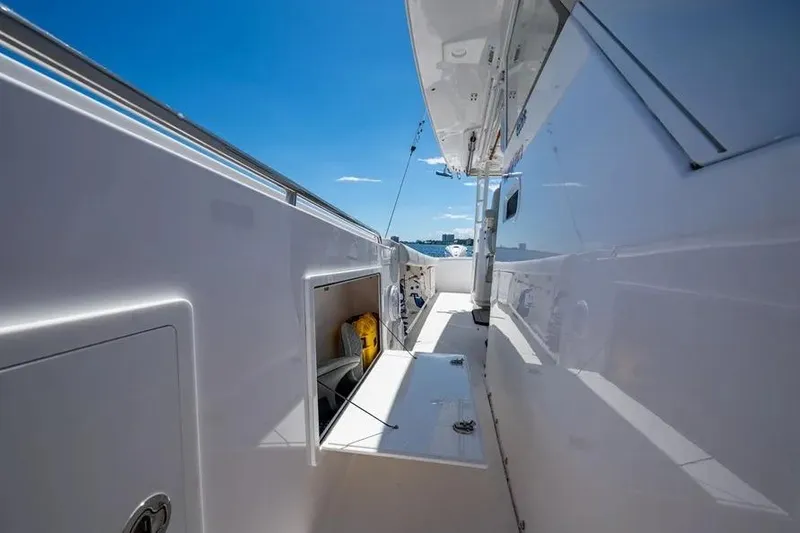 Slide: The Image of 2019 Everglades 435 Center Console boat deck with storage compartments, under clear blue sky. - 11
