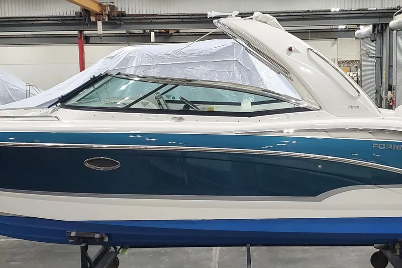 The Image of 2009 Formula 310 Bowrider boat in a warehouse, featuring sleek blue and white design. - 1