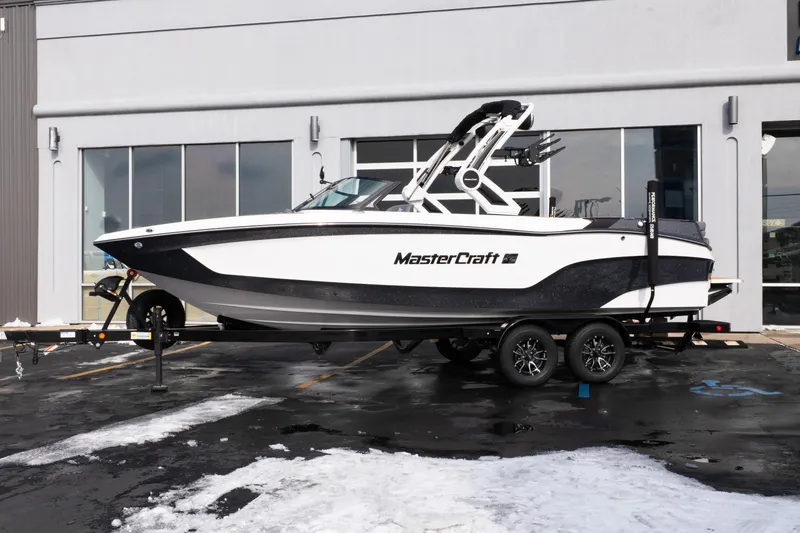 Slide: The Image of 2026 MasterCraft XT24 boat on trailer, parked outside a building. - 1