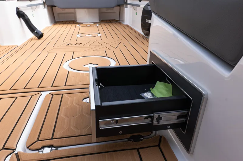 Slide: The Image of 2026 MasterCraft XT24 boat interior with open storage drawer on teak flooring. - 15
