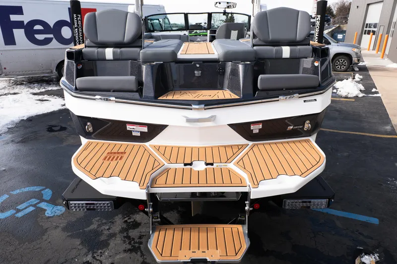 Slide: The Image of 2026 MasterCraft XT24 boat rear view with teak deck and seating, parked outdoors. - 3