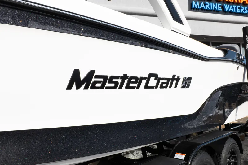 Slide: The Image of 2026 MasterCraft XT24 boat side view with logo, displayed outdoors. - 54