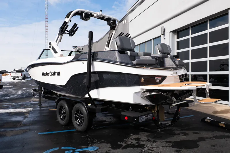 Slide: The Image of 2026 MasterCraft XT24 boat on trailer, parked outside a garage. - 59