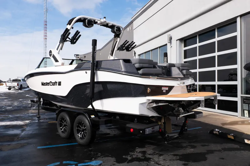 Slide: The Image of 2026 MasterCraft XT24 boat on trailer, parked outside a modern building. - 66