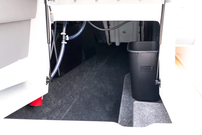 Slide: The Image of 2026 MasterCraft XT24 interior storage area with black bin and visible tubing. - 8