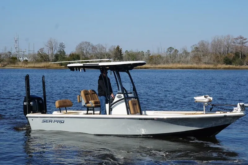 Slide: The Image of 2022 Sea Pro 228 Bay boat cruising on a calm lake with trees in the background. - 7