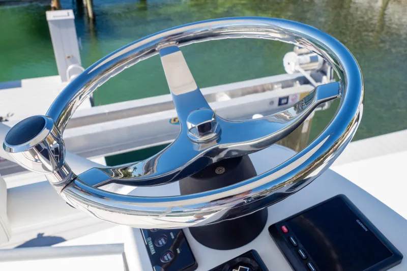 Slide: The Image of Steering wheel of a 2015 Intrepid 400 Center Console boat, docked by water. - 114