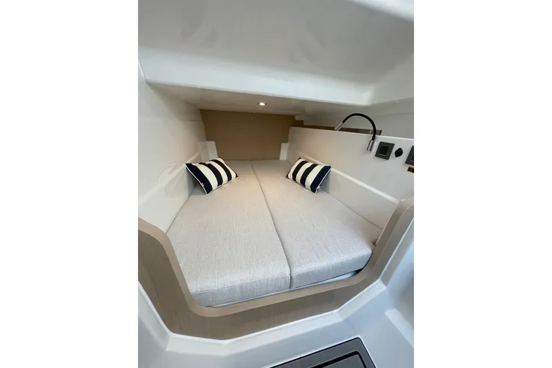 Slide: The Image of 2026 Jeanneau TH33 cabin interior with cozy bed and striped pillows. - 29