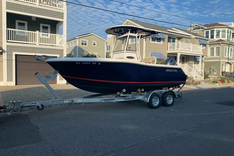 The Image of 2023 Release 210 RX boat on trailer, parked in residential area. - 1