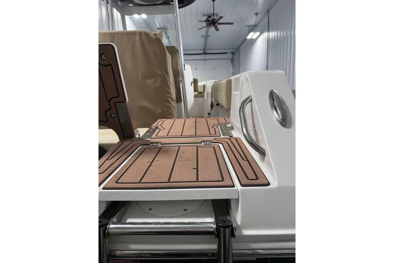 Slide: The Image of 2021 Release 210 RX boat interior with teak flooring in a well-lit storage facility. - 10