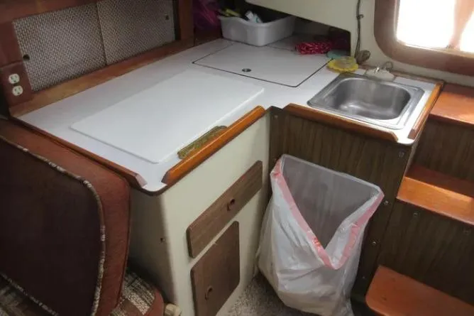 Slide: The Image of 1974 Pearson 30 sailboat galley with sink, countertop, and storage. - 12