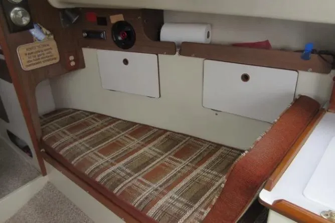 Slide: The Image of 1974 Pearson 30 sailboat interior with plaid cushion and storage compartments. - 13