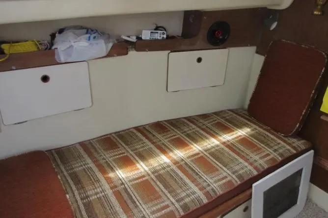 Slide: The Image of 1974 Pearson 30 sailboat interior with plaid cushions and storage compartments. - 14