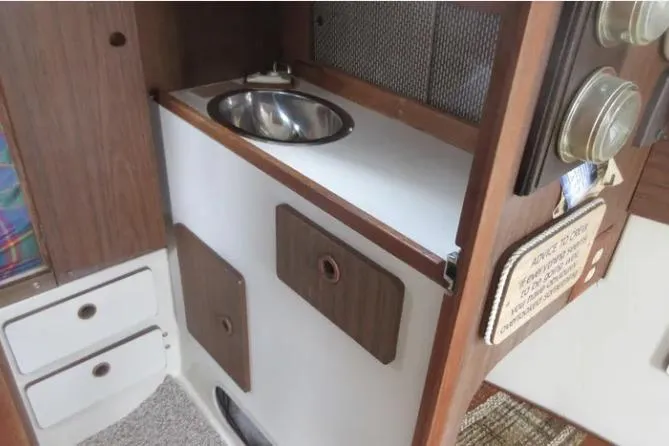 Slide: The Image of 1974 Pearson 30 yacht interior with compact sink and storage cabinets. - 15