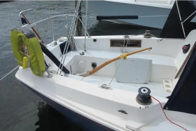 Slide: The Image of 1974 Pearson 30 sailboat cockpit with tiller and life preserver, docked on calm water. - 3