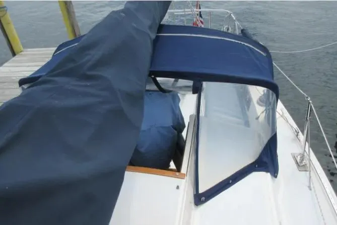 Slide: The Image of 1974 Pearson 30 sailboat with blue canvas cover docked by the water. - 7