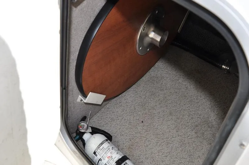 Slide: The Image of Storage compartment in 2021 Stingray 201 DS boat with fire extinguisher and table. - 18