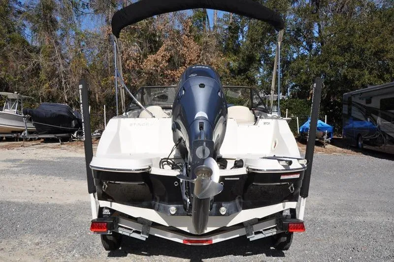 Slide: The Image of 2021 Stingray 201 DS boat rear view with outboard motor in a parking area. - 3