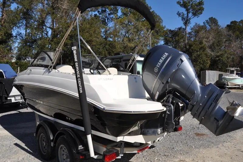 Slide: The Image of 2021 Stingray 201 DS boat with Yamaha outboard motor on trailer, parked outdoors. - 4